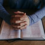 betende Hände auf einer geöffneten Bibel
